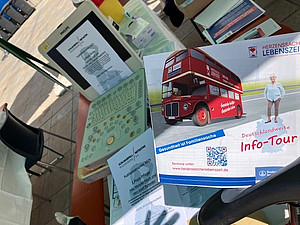 Flyer der Info-Tour „Herzenssache Lebenszeit“ neben Ultraschallgerät und Infomaterial auf einem Standtisch.