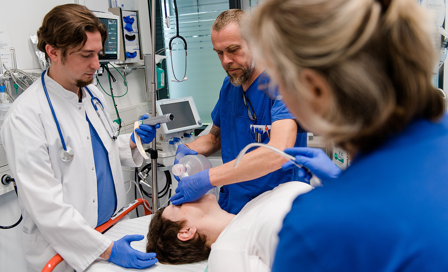 Leitender Oberarzt und Pflegekräfte versorgen eine Patientin.
