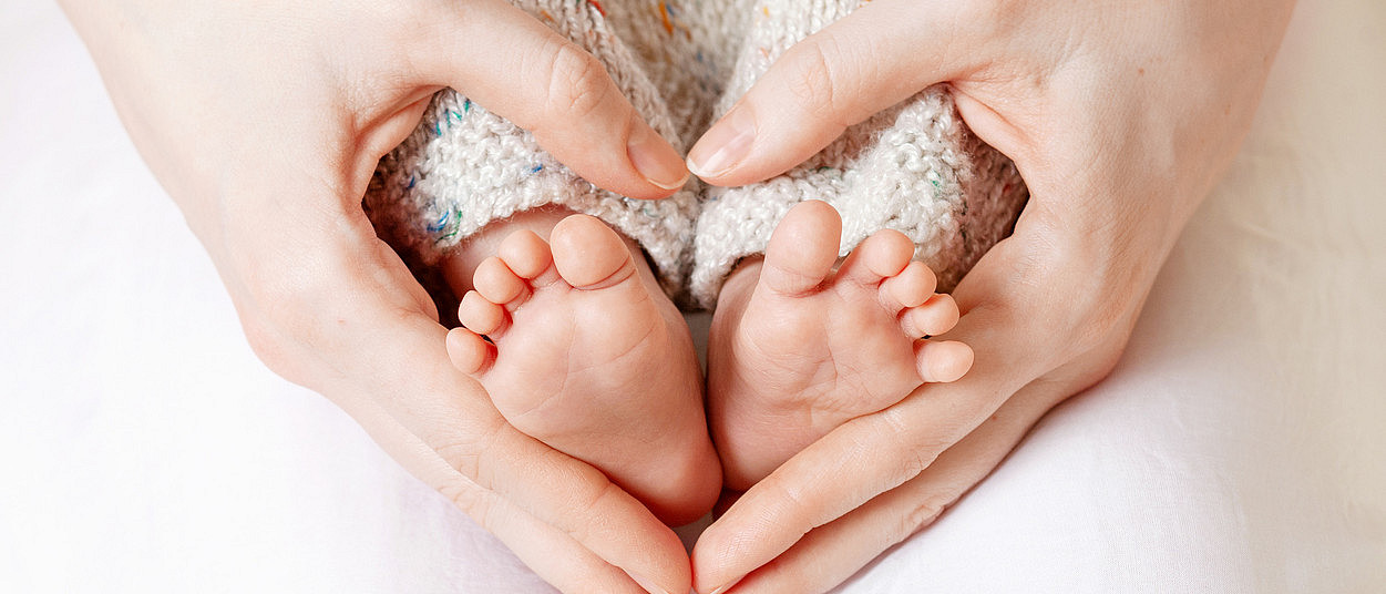 Mutter hält Babyfüße (Liudmila Fadzeyeva/iStock)