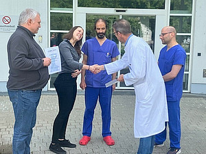 Prof. Schlachetzki gratuliert Preisträgerin, daneben stehen Kolleg:innen aus dem Pflegeteam.