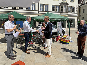 Prof. Schlachetzki und Prof. Pels überreichen einem Preisträger eine Urkunde bei der Verleihung am Neupfarrplatz.