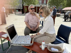 Medizinische Fachkraft führt auf dem Neupfarrplatz bei einem Mann eine Ultraschalluntersuchung durch.
